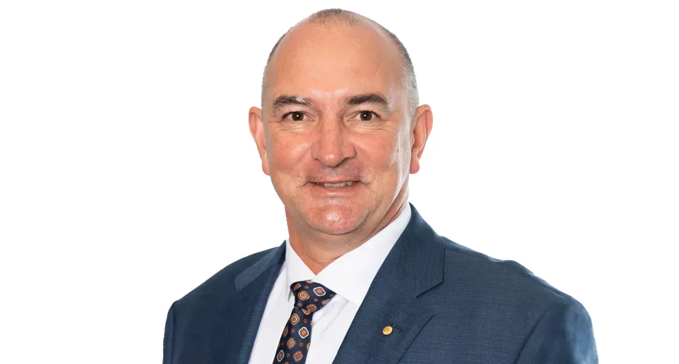 Tracey Hayes wearing a blue top and black blazer on a white background