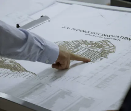 Tight View Of Besix Watpac Project Manager Pointing At Plans For JCU Engineering And Innovation Plac