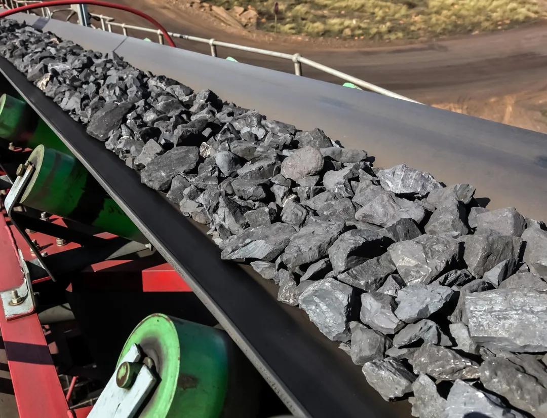 Manganese ore travelling down a conveyor belt
